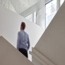 Man at staircase with glass at Leiden University College The Hague