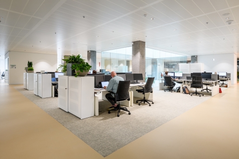 Open-plan office with the fall-through glass wall around the atrium in the background.